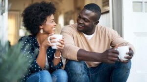 couple smiling at each other drinking coffee