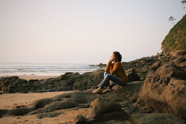 woman sitting on beach looking thoughtful