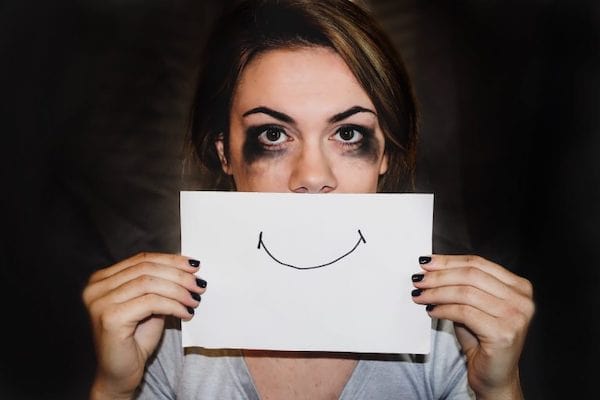 woman crying holding up image of smiling face