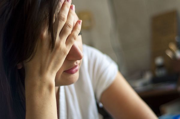 woman looking stressed with hand on forehead-min