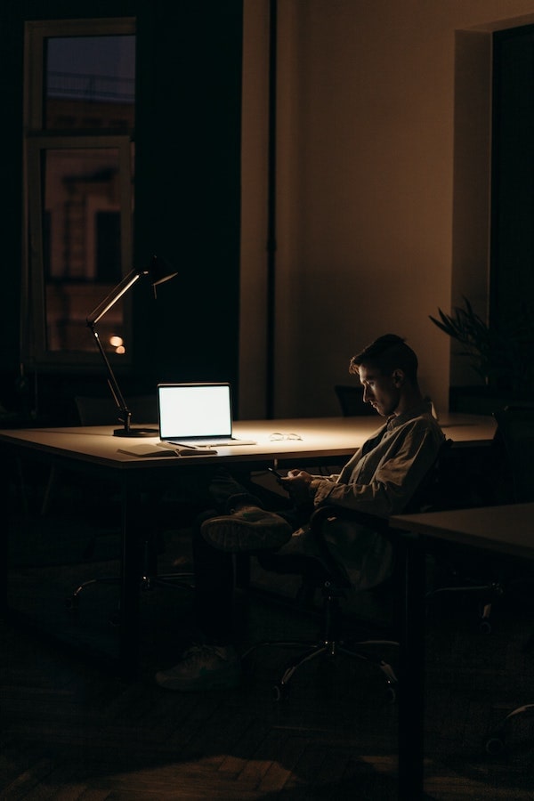 man sitting in dark next to work from home desk
